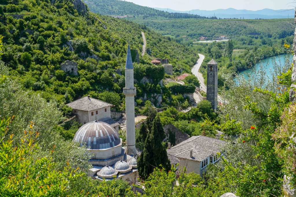 Vista panorámica de Počitelj, un pintoresco pueblo otomano en Herzegovina con casas de piedra, una torre de vigilancia y el río Neretva al fondo.