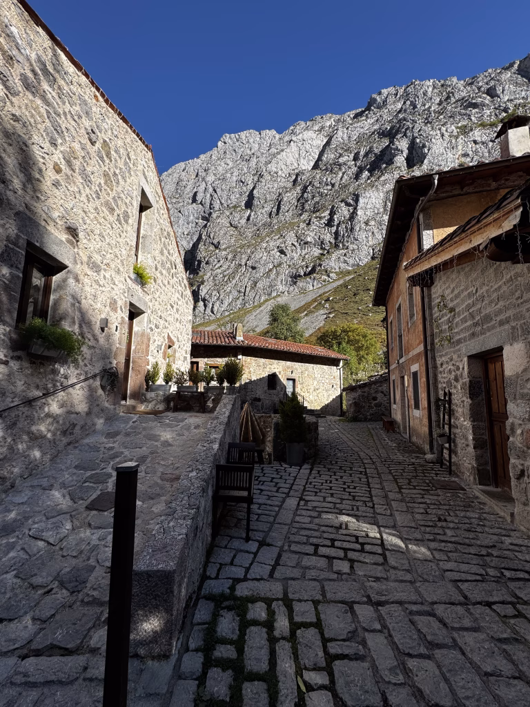 Calle adoquinada de Bulnes de Abajo rodeada de casas tradicionales de piedra en los Picos de Europa.