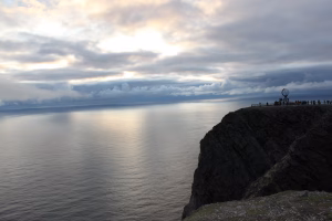 Acantilado de Cabo Norte con el monumento del globo de Nordkapp frente al Océano Glacial Ártico bajo el sol de medianoche.